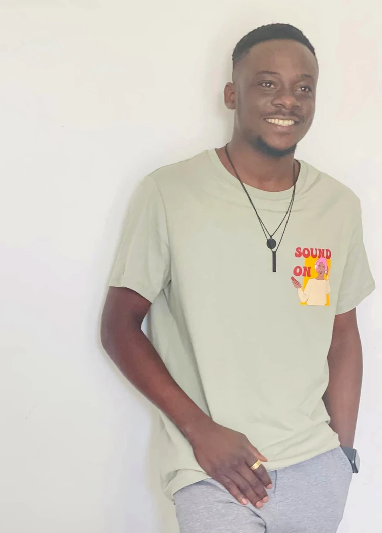 Johnson Adegboye Adelere smiling, leaning against a wall.
